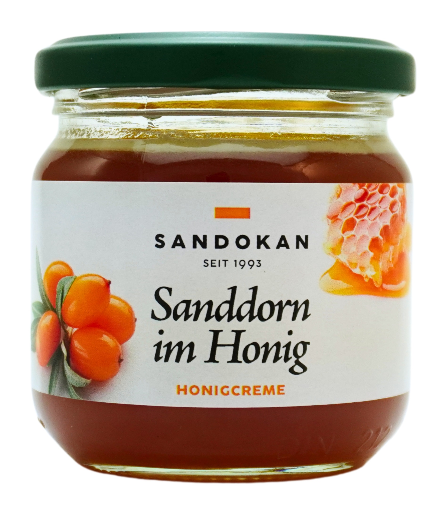 Ein Glas, gefüllt mit dunklem Honig, verschlossen mit einem grünen Deckel und beklebt mit einem weißen Etikett mit der Aufschrift "Sandokan seit 1993 Sanddorn im Honig Honigcreme". Links unten auf dem Etikett ein Sanddornzweig mit orangen Sanddornbeeren u